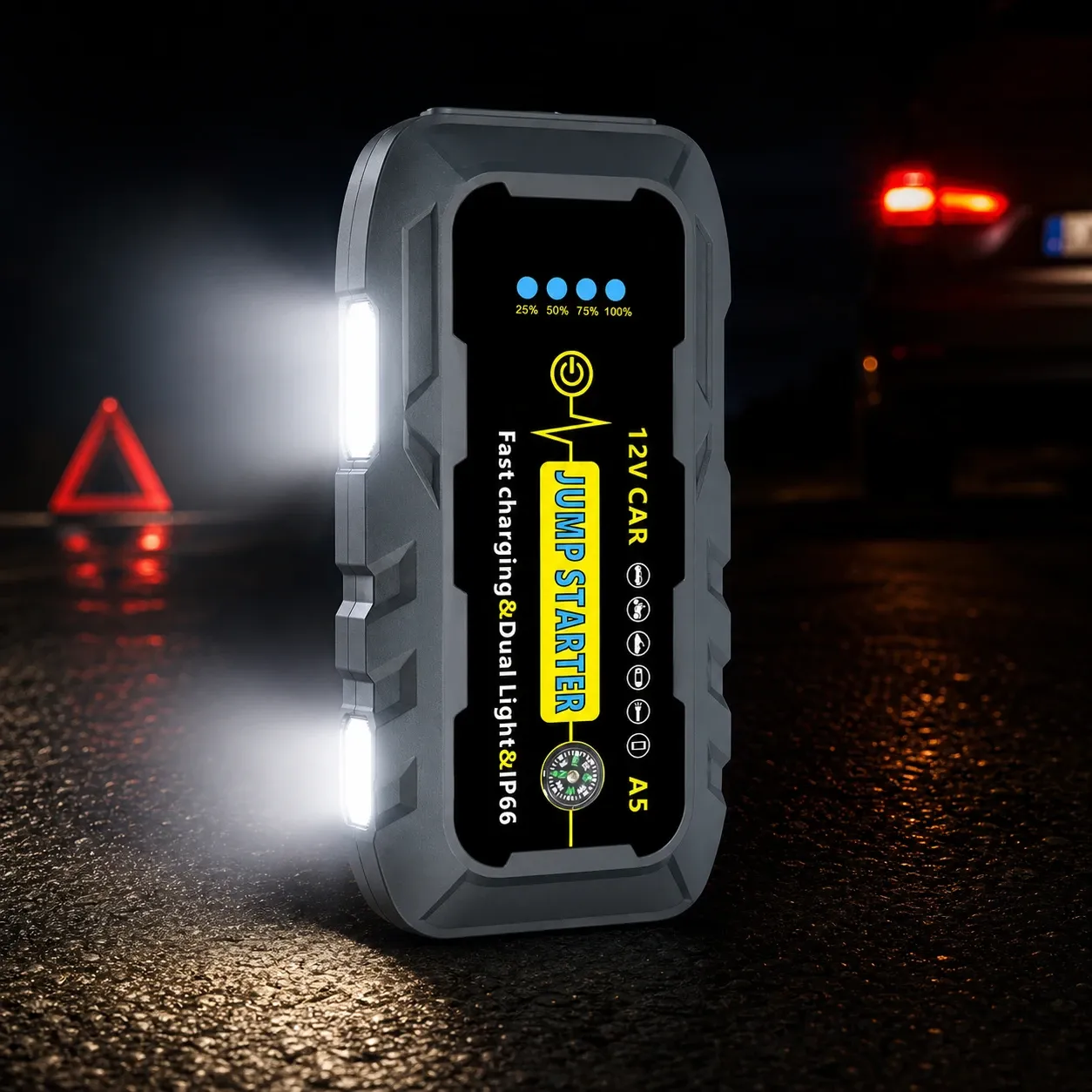 Compact 12V car jump starter with dual built-in lights shown standing on a wet road at night, with a warning triangle and car headlights blurred in the background.